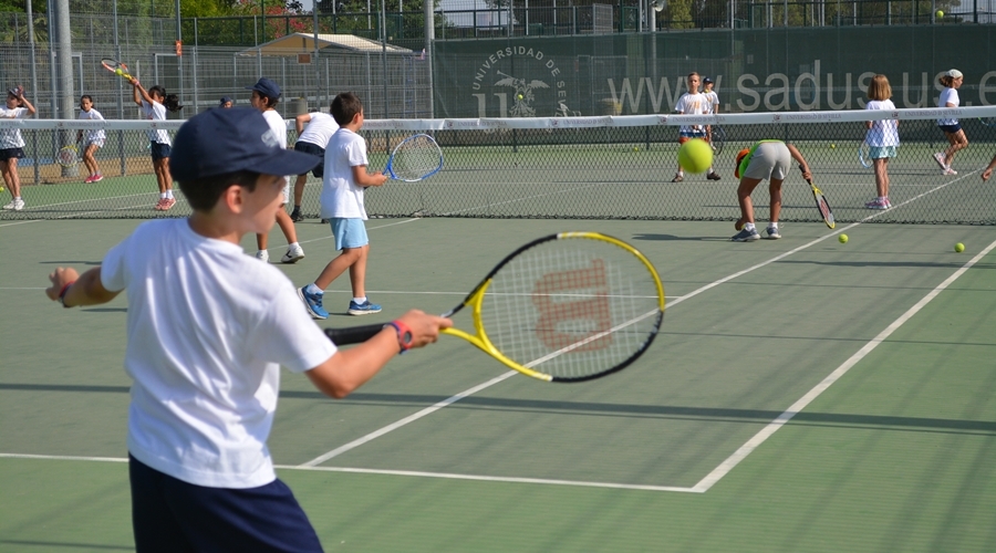 Niños practicando tenis de manera inical