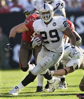 Raiders running back Bush races away from Buccaneers defenders during NFL game at in Tampa